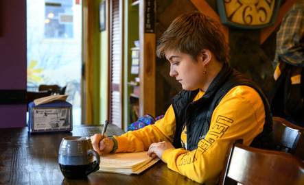 Journalism student writing at a local coffee shop