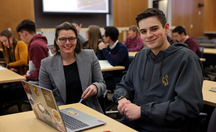 A professor and student pose for a picture in class