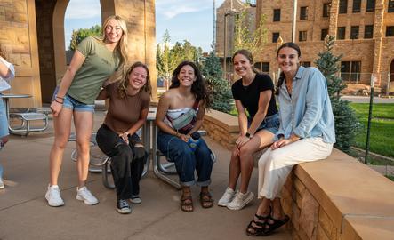 A group of students smiling for a photo outside of the dorms
