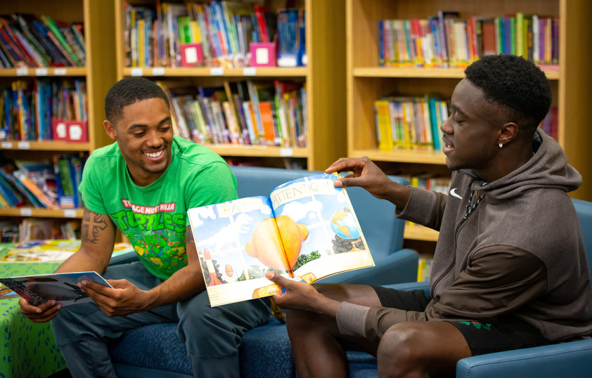 Two college students reading to elementary students