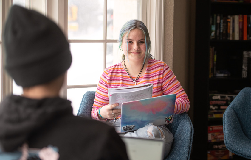 Student with laptop and book in lap