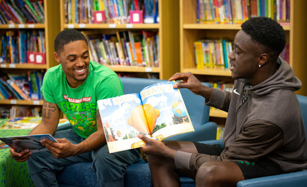 Two college students reading to elementary students
