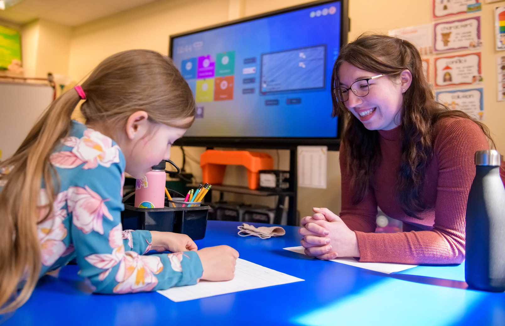 Teacher reading with student at table