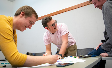 Three marketing students work on a project at a table