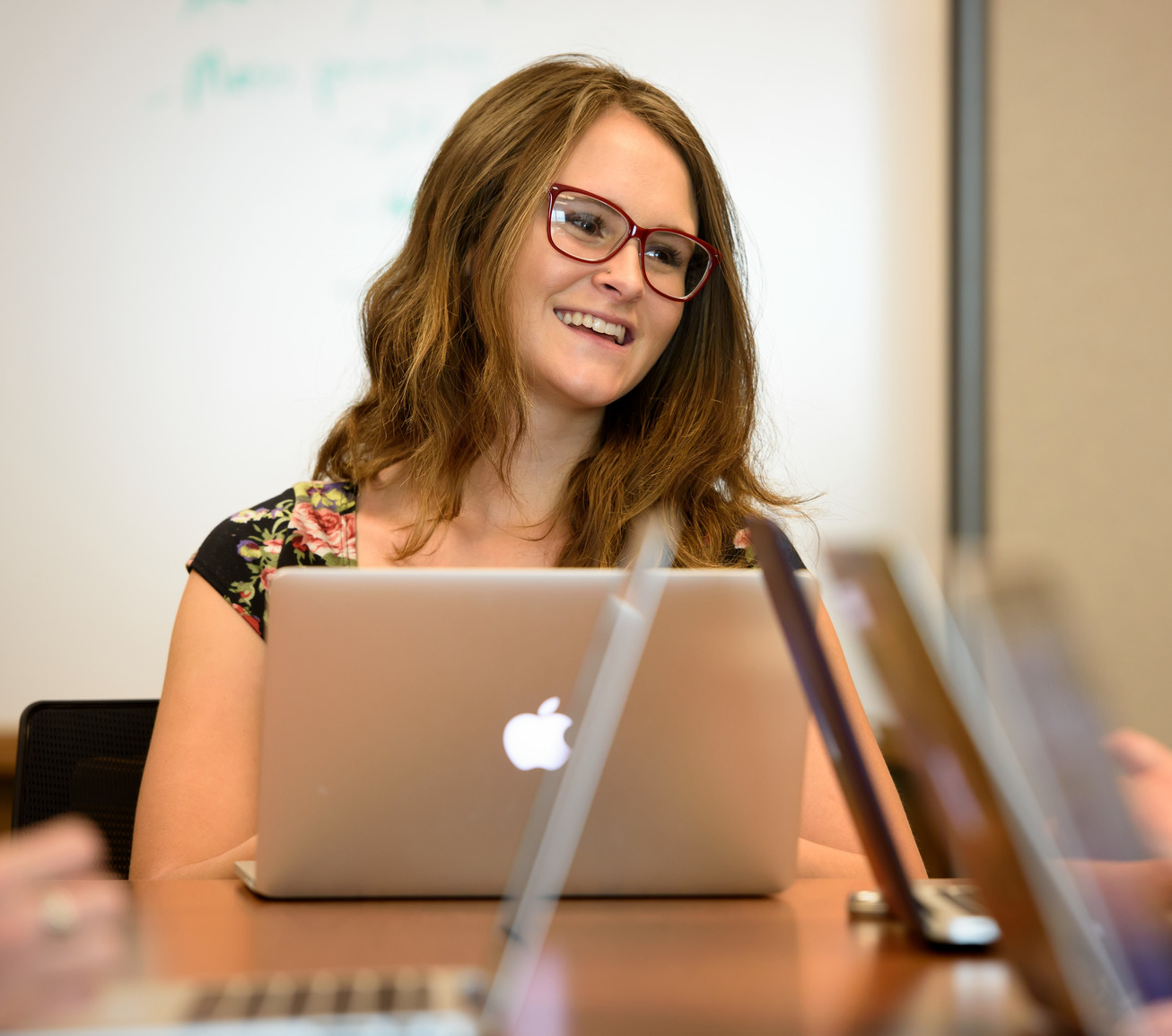 A student works on a laptop while smiling during class