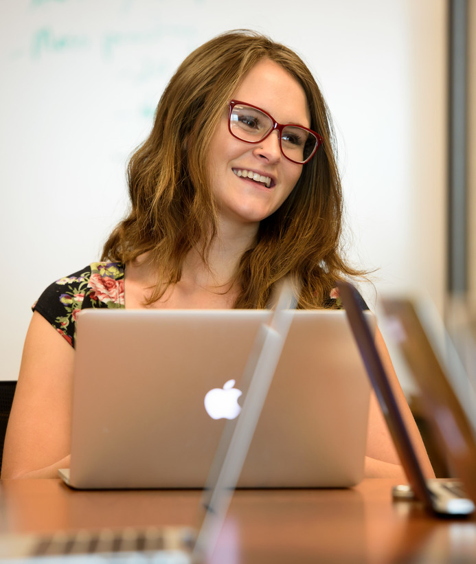 Marketing communication student smiles on their laptop