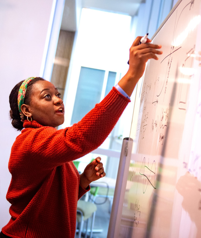 Mathematics student does math on a dry erase board