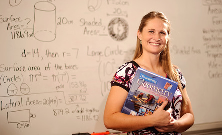 Math student smiles for the camera with a textbook