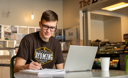 Student writes in their notebook at a cafe