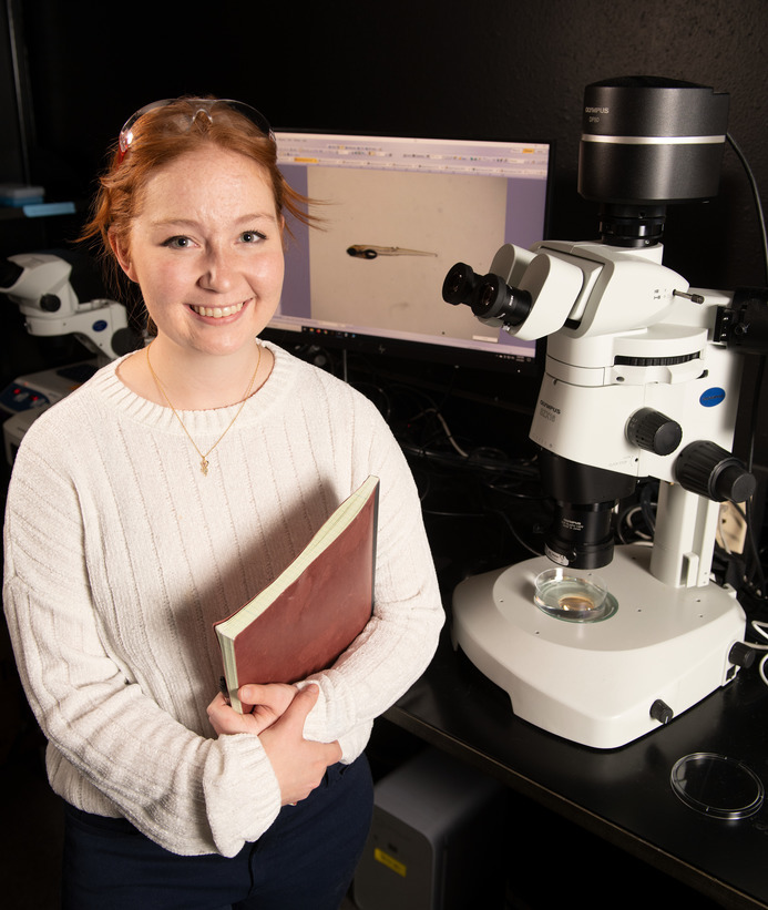 A student smiles for a photo in a lab