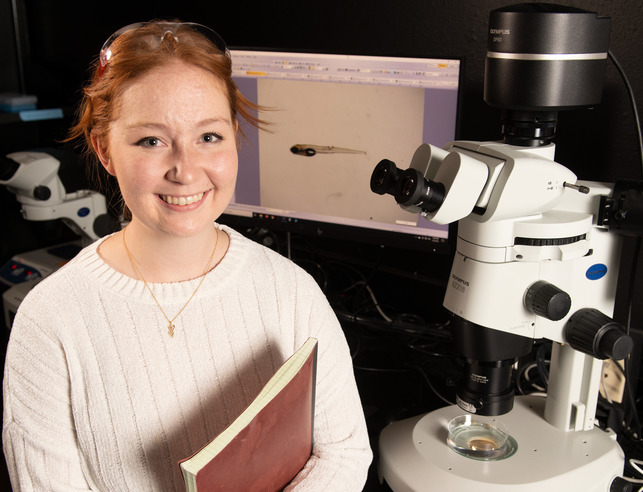 A student smiles for a picture in a lab