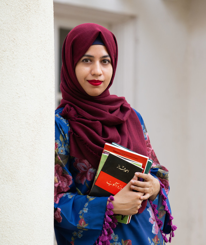 A student smiles softly while holding a book