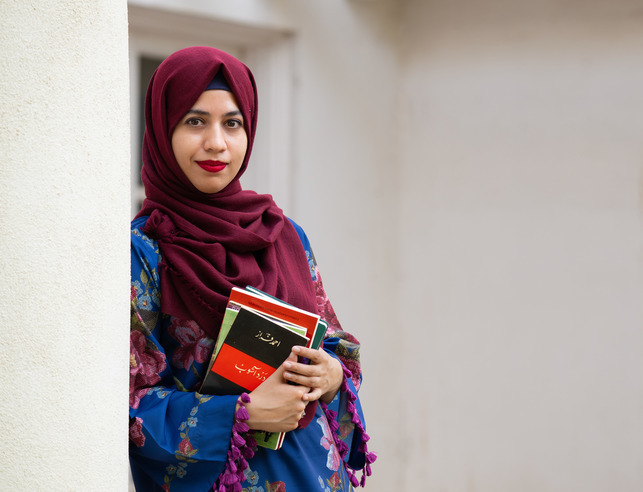A student smiles softly while holding a book