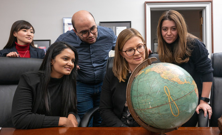 A group of people examine a globe together