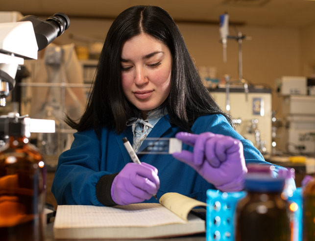 A student examines a slide in a lab