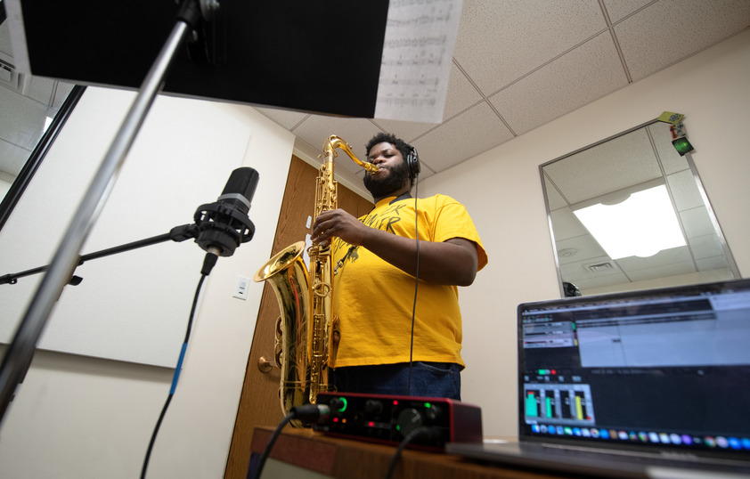 A student plays the saxophone in a recording studio