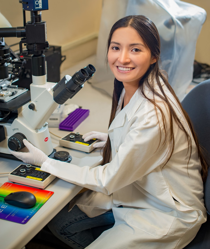 A student smiles for a photo while in a lab