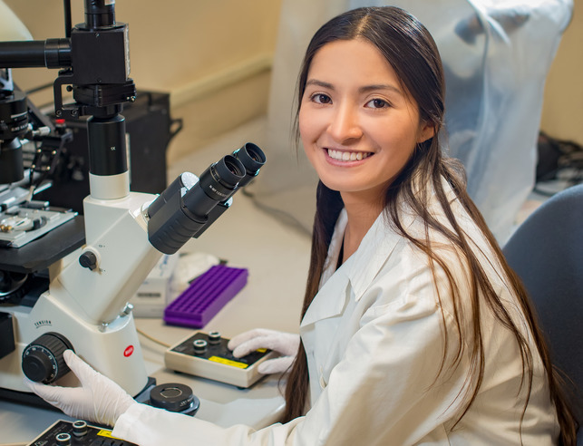 A student smiles for a photo while in a lab