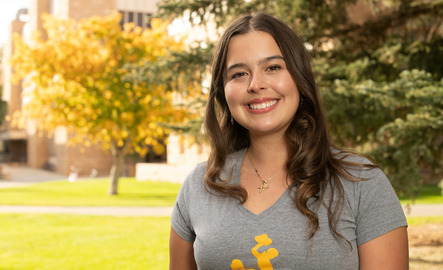 A student smiles for a photo while wearing a Unviersity of Wyoming shirt