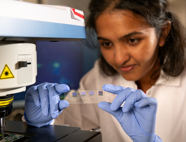 Student holds up a slide with microchips
