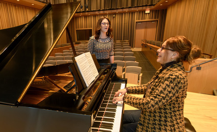 Student singing while music professor plays the piano