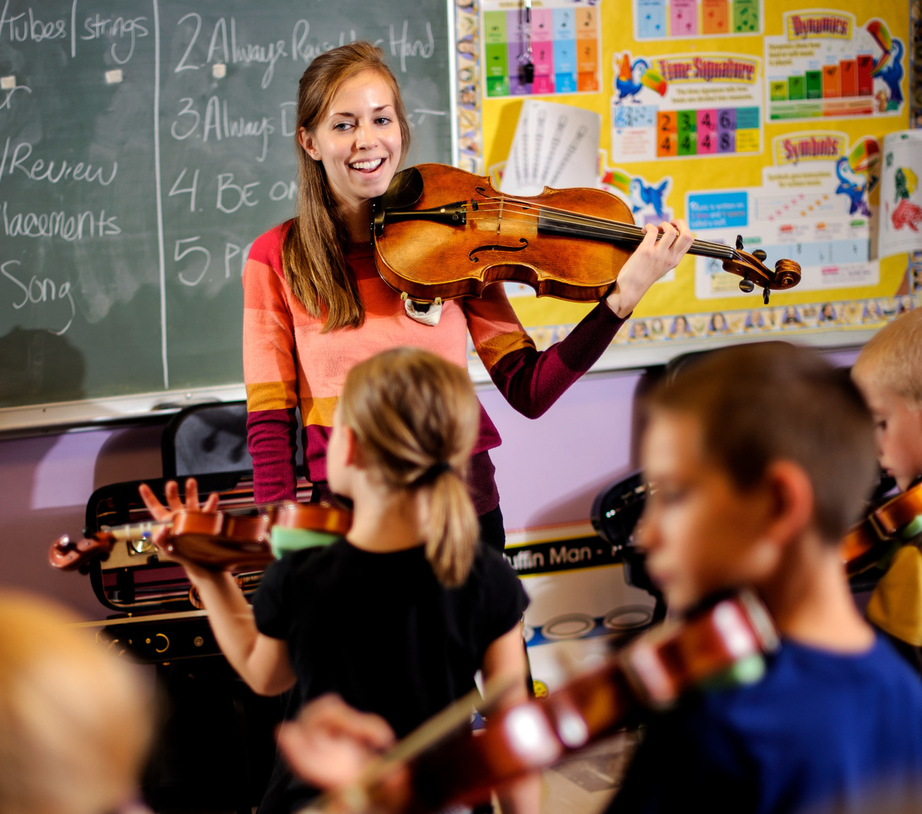 Student teaches a room of children to play violin 