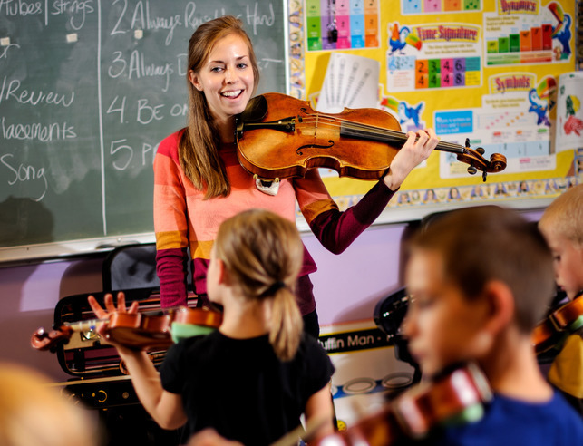 UW student teaches a room of children to play violin