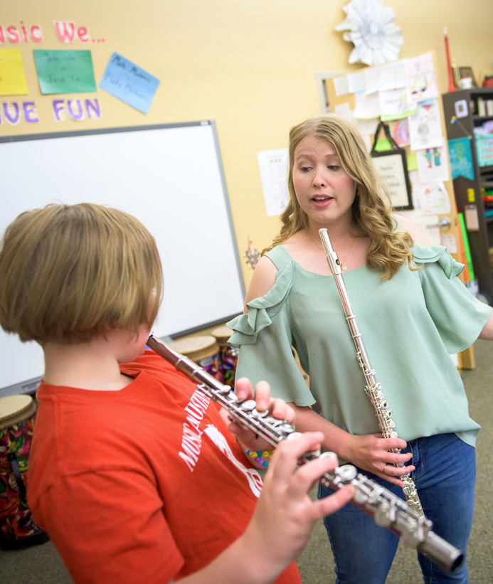 UW music education student teaches elementary student to play the flute
