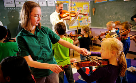 Music education student teaches elementary student to play the violin