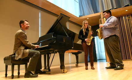 UW faculty and students play the piano and saxophones on a stage