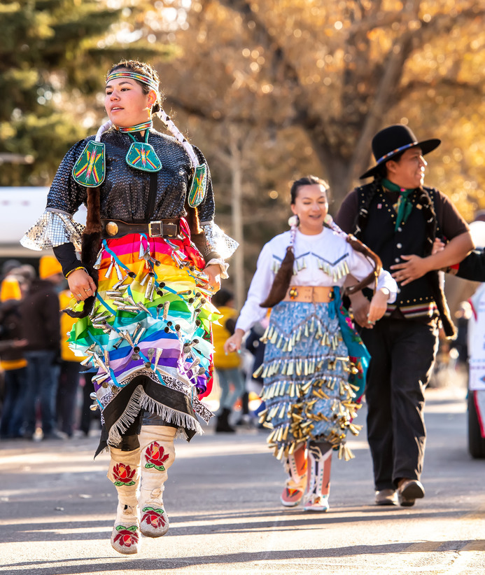 A group of Native American students wearing regalia walk in UW homecoming parade