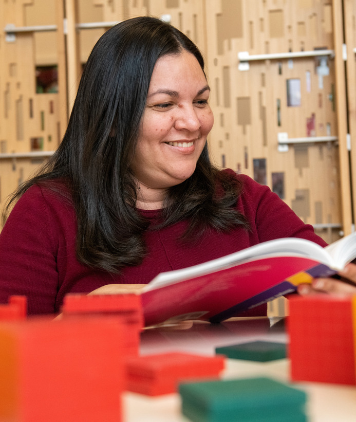 A teacher smiles while reading a book