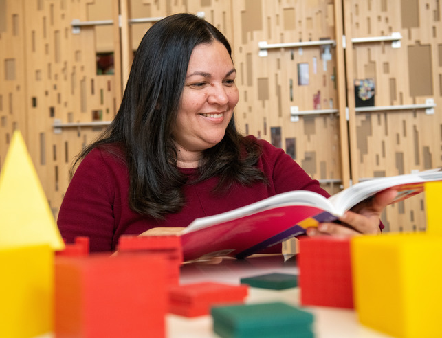 A teacher smiles while reading a book