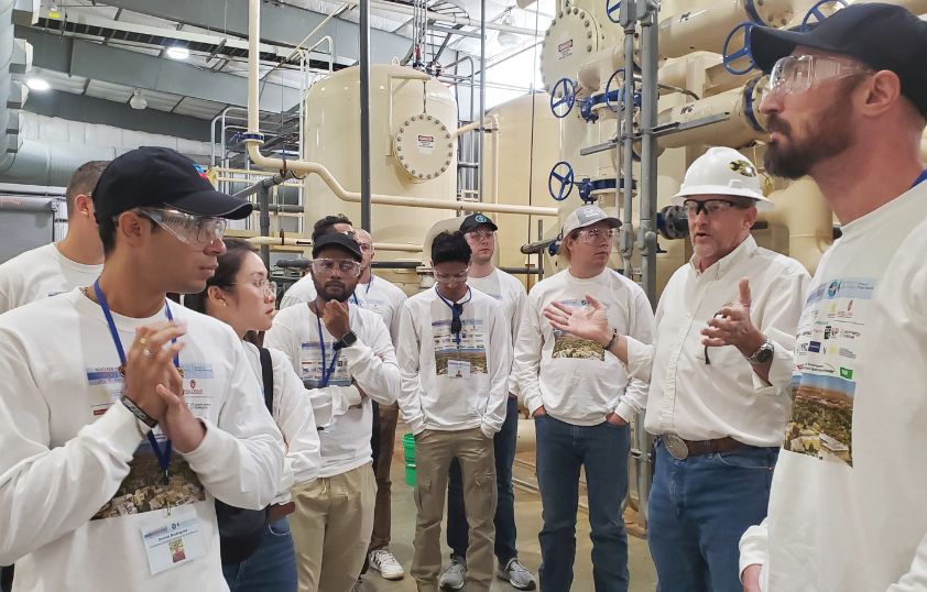 A professor talks to a group of students in a lab