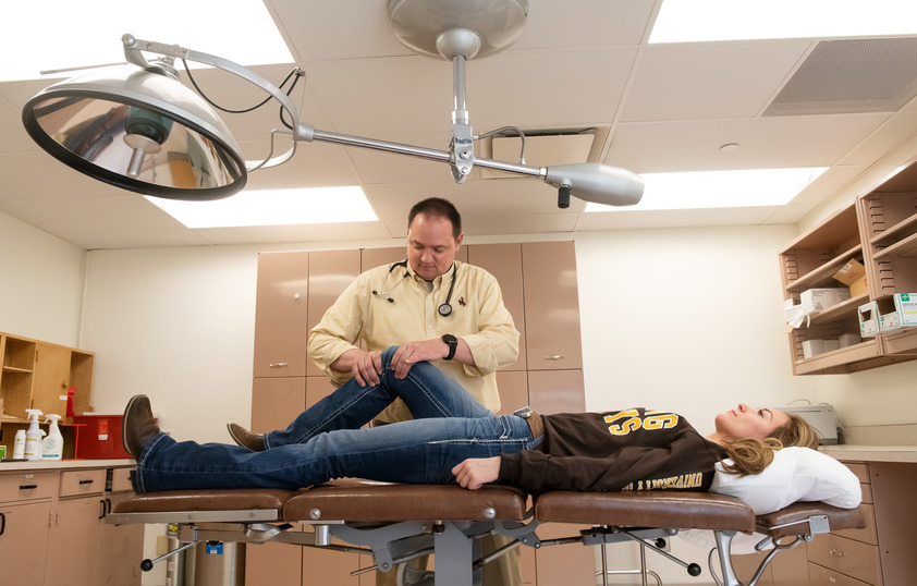 A nursing student examines a test student subject's knee.