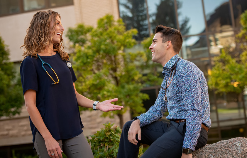 Two students talk together on a break from class outside.