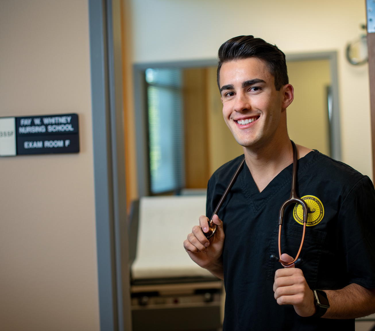 A student stands in the UW nursing building with their stethoscope.