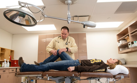 A nursing student examines a student's knee