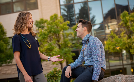 Two students talk together on a break from class outside