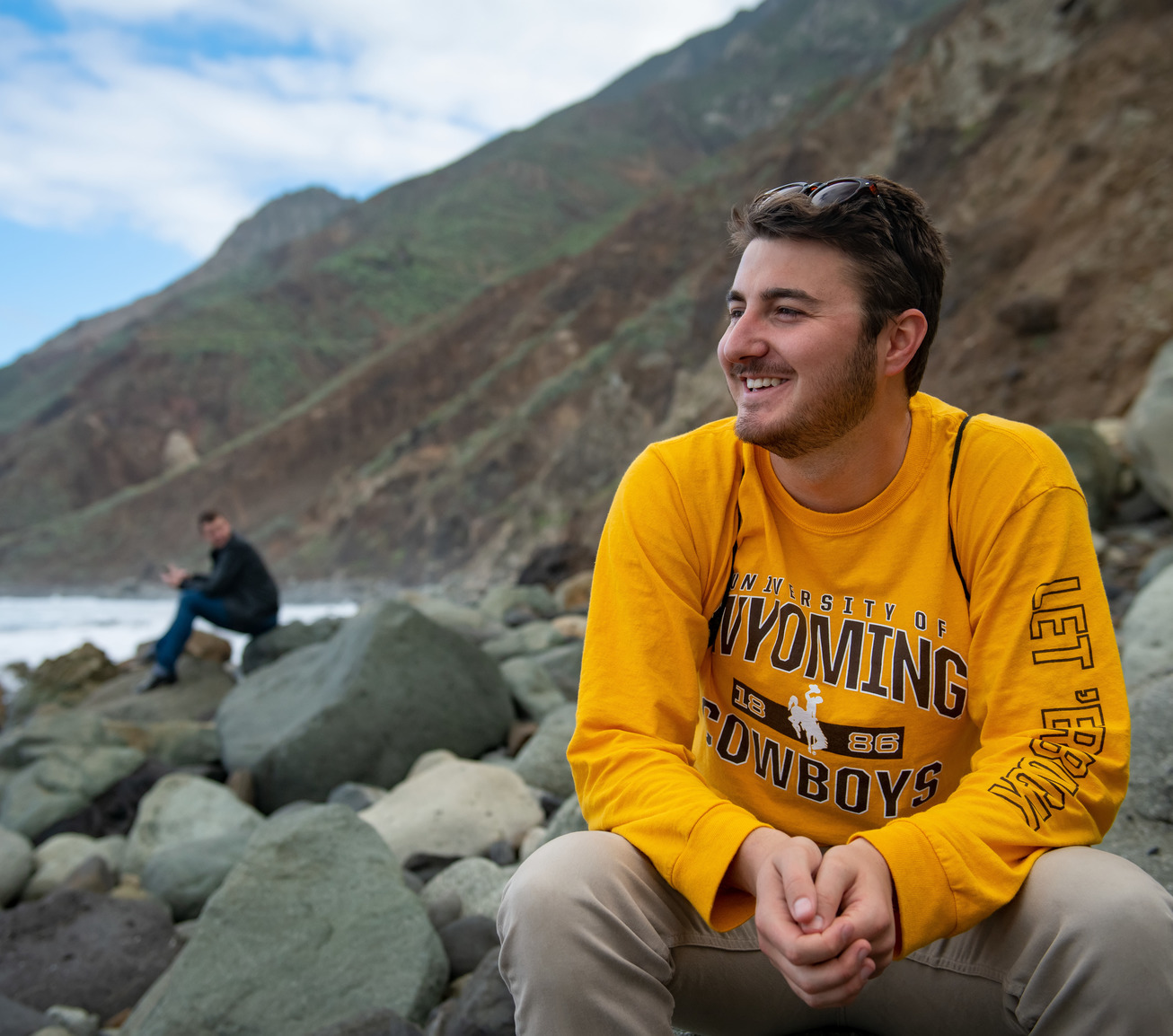 Student smiling off into the distance on a beach during a study abroad trip