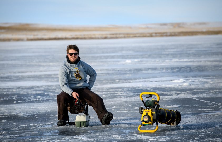 A student ice fishing smiles for a photo