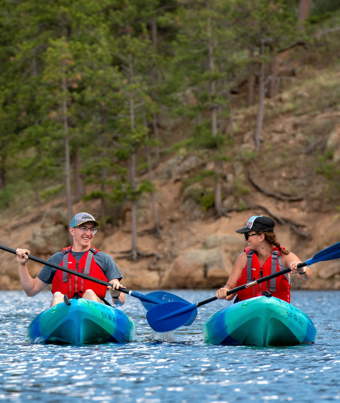 Two students smiling at each other while kayaking