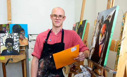 Student poses with their paintings