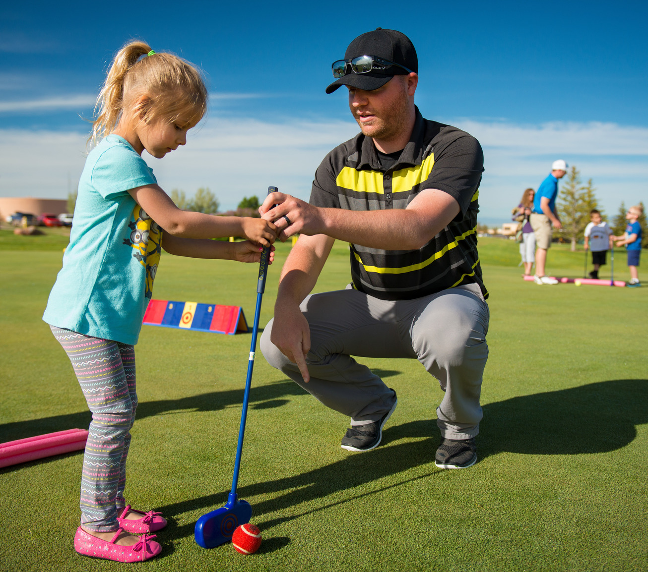Teacher helping young student golf