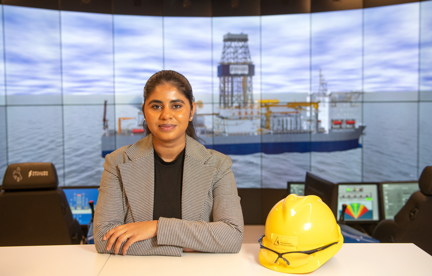 A student smiles in front of the drilling simulator