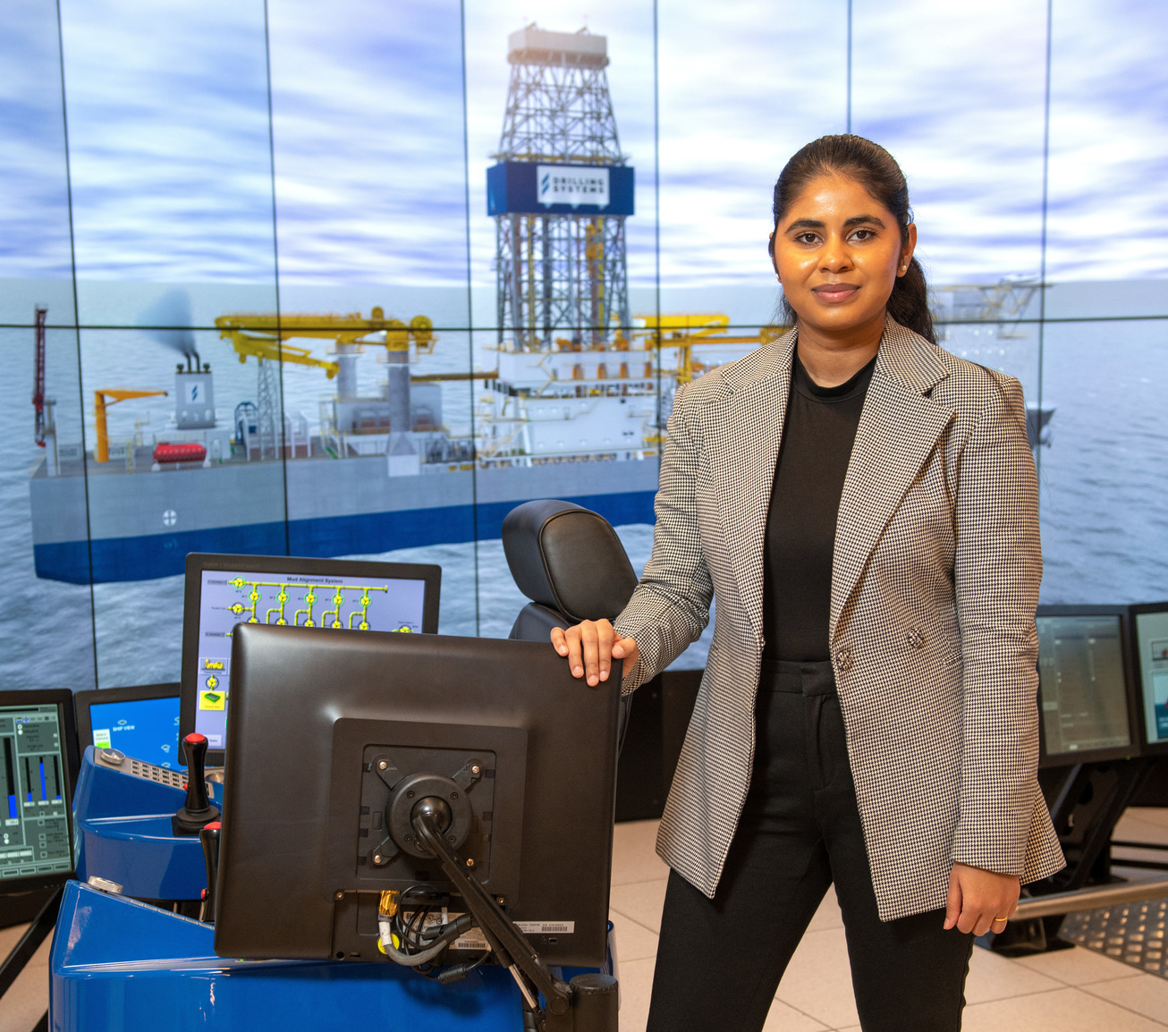 A student poses for a picture in front of the drilling simulator