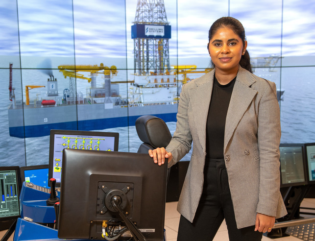 A student poses for a picture in front of the drilling simulator