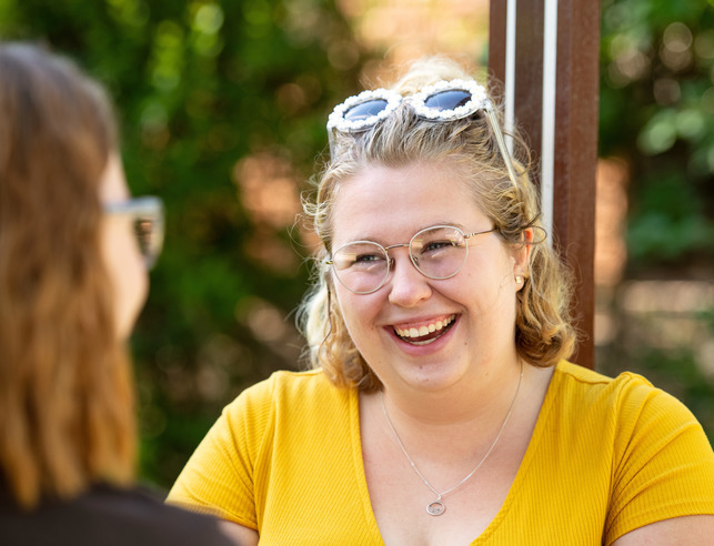 Student smiling as they talk to another student