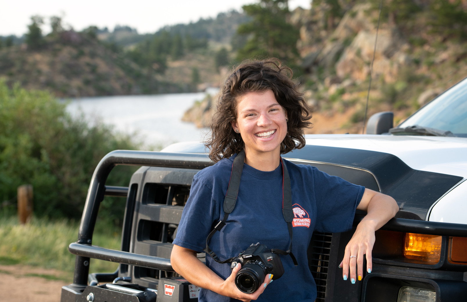 Photographer posing with camera while leaning against van