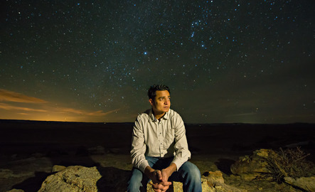 Person sits outside at night under the stars
